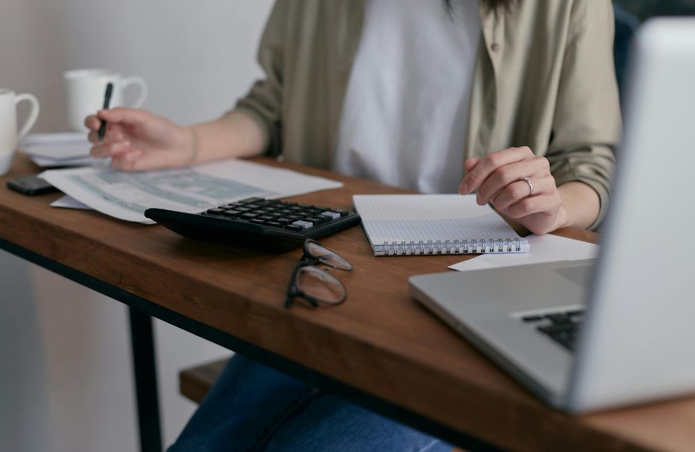 Pessoa analisando documentos financeiros com laptop e calculadora sobre a mesa, representando a rotina de adaptação contábil e fiscal das empresas brasileiras às exigências da IFRS 16.