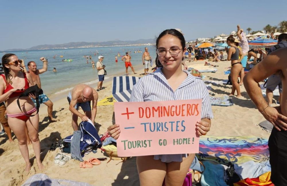 Manifestantes em praia da Espanha com faixas contra o turismo massificado.